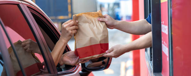 Hand Man in car receiving coffee in drive thru fast food restaurant. Staff serving takeaway order for driver in delivery window. Drive through and takeaway for buy fast food for protect covid19. Hand Man in car receiving coffee in drive thru fast food restaurant. Staff serving takeaway order for driver in delivery window. Drive through and takeaway for buy fast food for protect covid19. fast food stock pictures, royalty-free photos & images