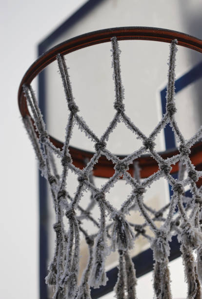 Basketball hoop on the wall of a frame wooden building. Basketball hoop in the snow and icicles.