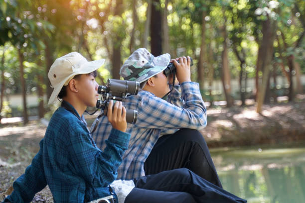 istock Two Asian boys use binoculars to study the local birds in a community forest. Soft and selective focus. 2192042742