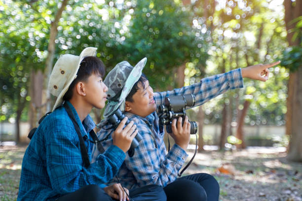 istock Two Asian boys use binoculars to study the local birds in a community forest. Soft and selective focus. 2192042743