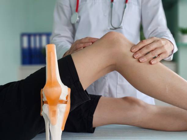 istock Doctor examining a patient knee with a medical model 2192045481