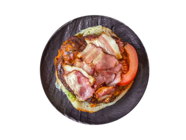 Juicy burger with beef patty, tomatoes, cheese, bacon, salt and spices on a white background