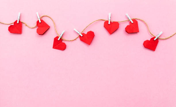 istock Red paper hearts hanging on a rope against pink background 2192049866