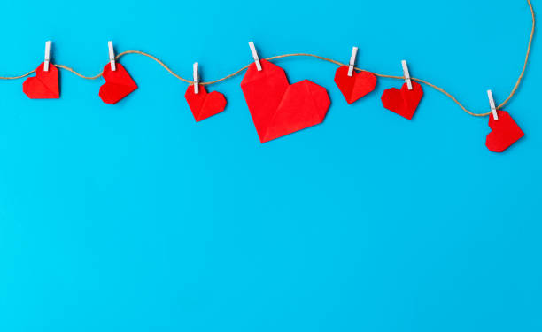 istock Red paper hearts hanging on a rope against blue background 2192049899