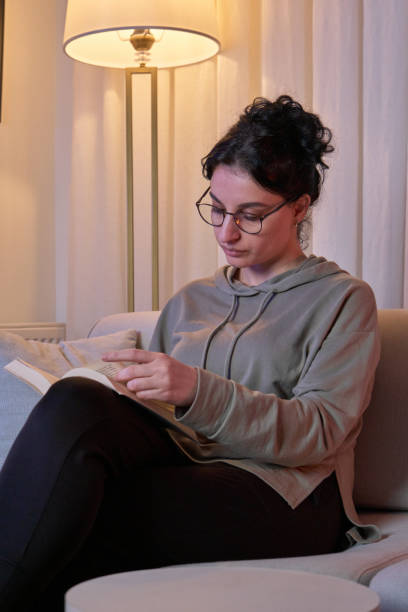 istock Serene Evenings: A Woman Relaxing with a Book in a Cozy Atmosphere 2192051720