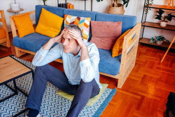 istock Man having bad feelings alone at home in living room while sitting on floor 2192054920