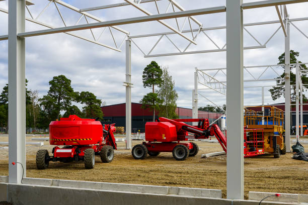 Modern red self propelled construction hydraulic articulating arm boom lifts platforms on modern metal frame building construction site