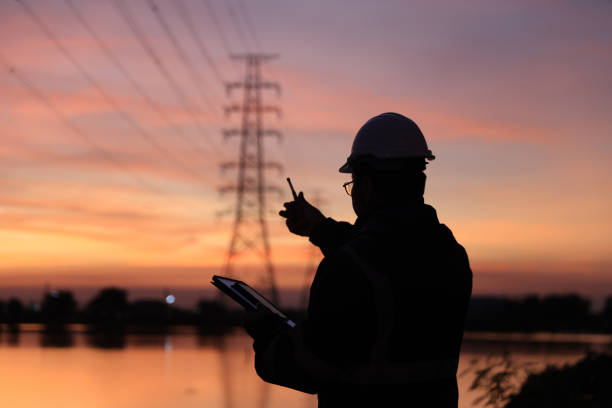 istock Silhouette electrical engineer working at the site of electricity pylon with orange sky 2192057919