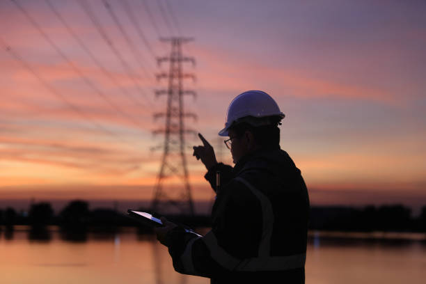 istock Silhouette electrical engineer working at the site of electricity pylon with orange sky 2192057926