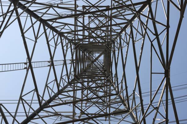 Power line tower on a sunny day, view from below. High voltage electric poles under the blue sky