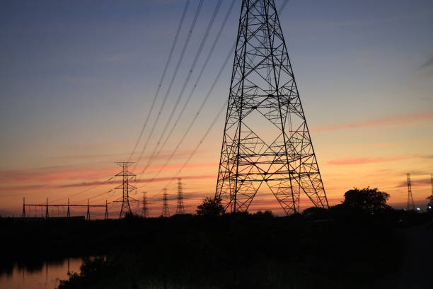 Low-angle view of two illuminated electricity pylons against a vibrant twilight sky