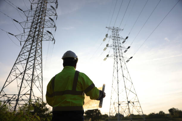 istock Senior electrical engineer with PPE uniform works on drawing at the power plant  of High voltage Electrical pole during sunset 2192058075