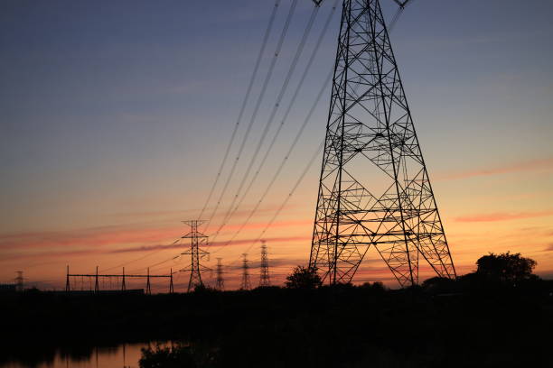 Low-angle view of two illuminated electricity pylons against a vibrant twilight sky