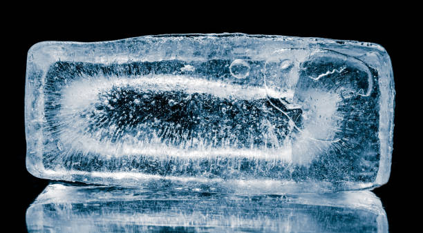 istock Natural textured ice block with frozen air bubbles structure and internal cavity isolated on a black background with reflection. 2192058350