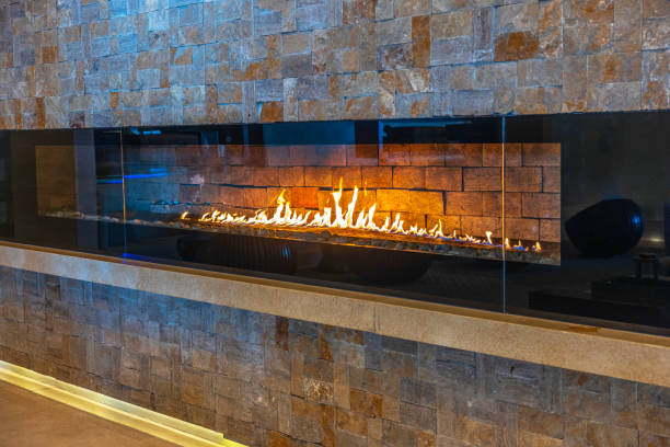 istock Modern linear gas fireplace with vibrant flames set against textured stone wall in cozy interior space hotel. Mexico. 2192059727