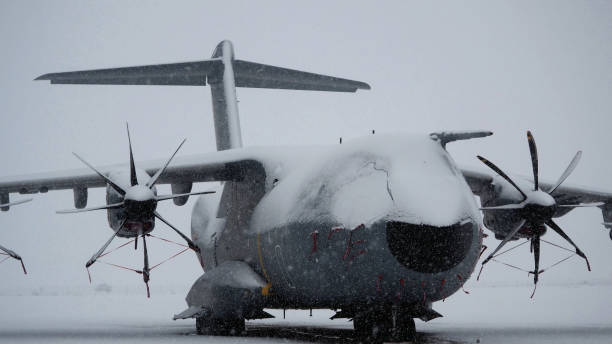 istock Snow-covered military transport aircraft on runway. 2192059772