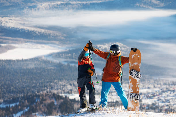 Backcountry splitboarder ascends mountain through forest and fresh powder snow, British Columbia
