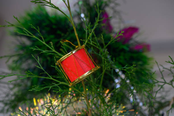 A vibrant red drum ornament dangles gracefully from a green branch, capturing the essence of the festive season.