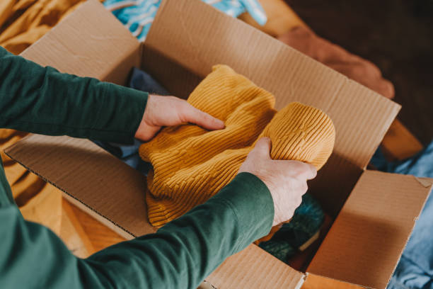 istock Unrecognizable man putting old clothes into box for charity or upcycling 2192069093