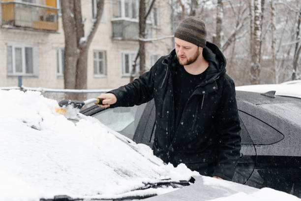 istock young man cleans car from snow 2192070163