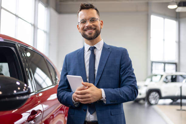 istock Salesman holding tablet in car dealership 2192076362