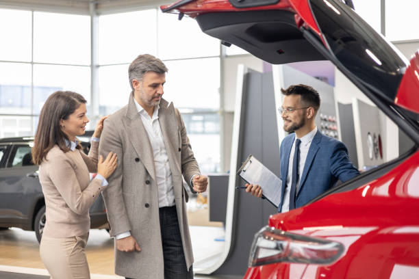 istock Salesman presents car trunk to couple 2192076371