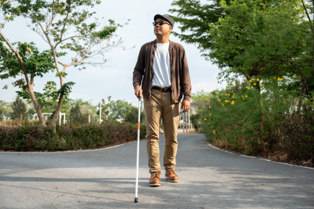 istock Young blind man walking in city with walking stick. Visually impaired man difficult to traveling on the road wearing sun glasses Cross the road cross the footbridge 2192085087