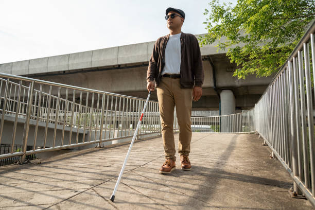 istock Young blind man walking in city with walking stick. Visually impaired man difficult to traveling on the road wearing sun glasses Cross the road cross the footbridge 2192085097