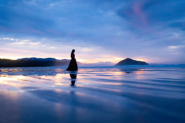 Elegant woman dances gracefully on the beach at low tide during a beautiful sunrise, Vancouver Island, British Columbia, Canada