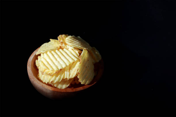 istock potato chips on a wooden plate with a black background 2192093682