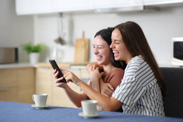 istock Happy interracial lesbian couple checking phone laughing at home 2192102608