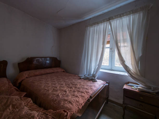 istock Uninhabited old house showing bedroom with two beds and open window 2192106654