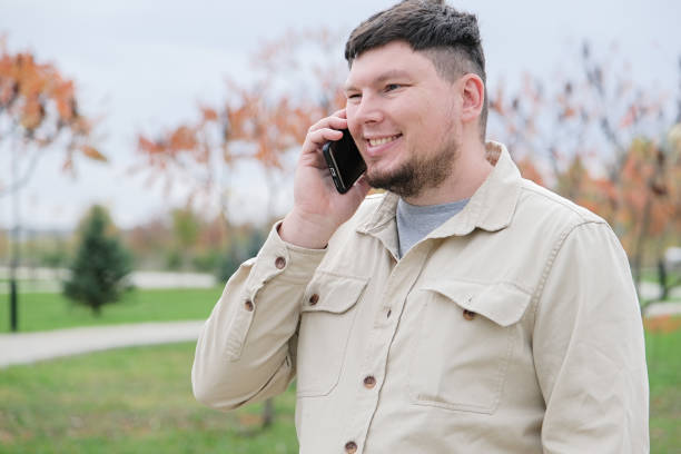 istock young caucasian man walking in the park and using smartphone 2192107574