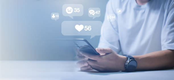 istock Close-up of man's hand using smartphone to play social media with emoticons or notifications popup. 2192109419