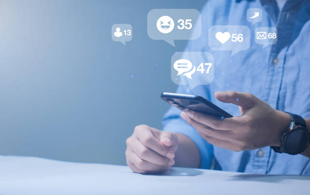istock Close-up of man's hand using smartphone to play social media with emoticons or notifications popup. 2192109534