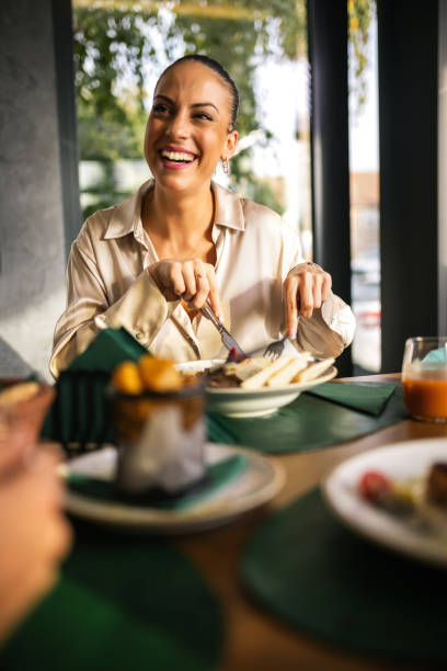 istock Beautiful woman eats lunch with her friends in a restaurant. She eats meat with salad. 2192109813