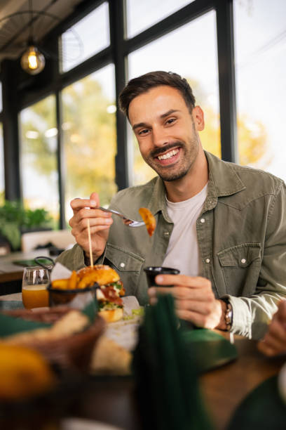 istock Man enjoying his lunch at a restaurant, sitting at a table with a delicious meal in front of him. 2192109891