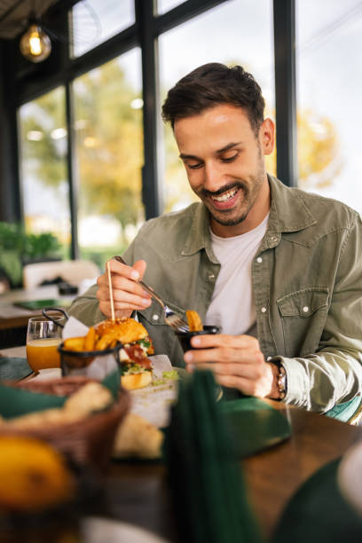 istock Man enjoying his lunch at a restaurant, sitting at a table with a delicious meal in front of him. 2192109892