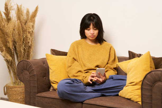 istock Young woman using smartphone while relaxing on sofa at home 2192110433