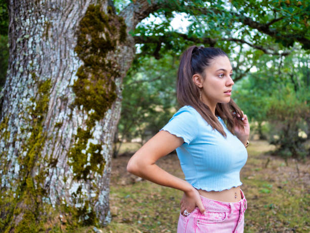 istock Young woman posing near a large tree in a forest 2192110542