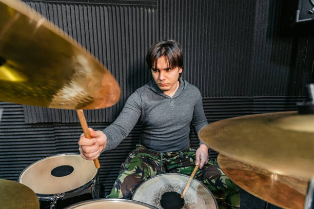 Drummer playing drums during a rock band rehearsal in a studio.