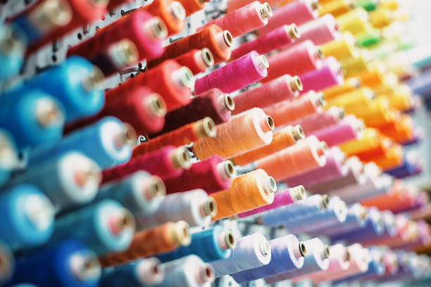 Colorful spools of thread showing a gradient of colors are arranged on a rack