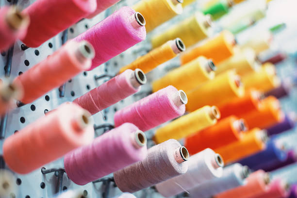 Colorful thread spools hanging on a wall pegboard, ready to be used in a tailor shop