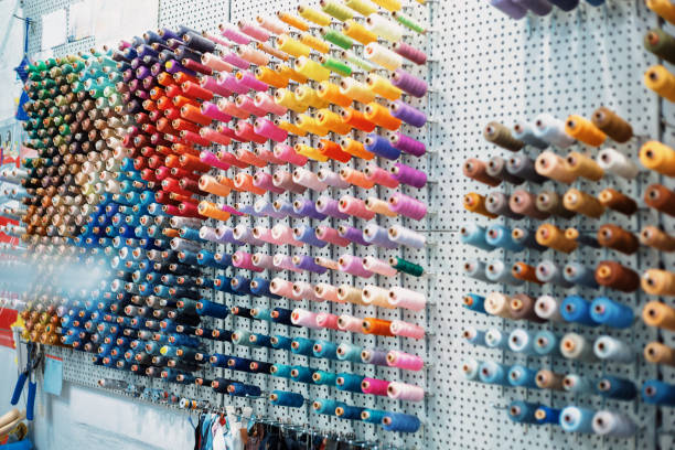 Many colorful thread spools hanging on a wall pegboard, ready to be used for sewing