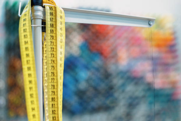 Yellow measuring tape hanging in a fashion design studio, ready to be used