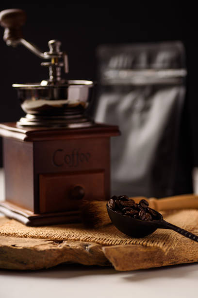 Roasted coffee beans, grinder and packaging bag on black background.