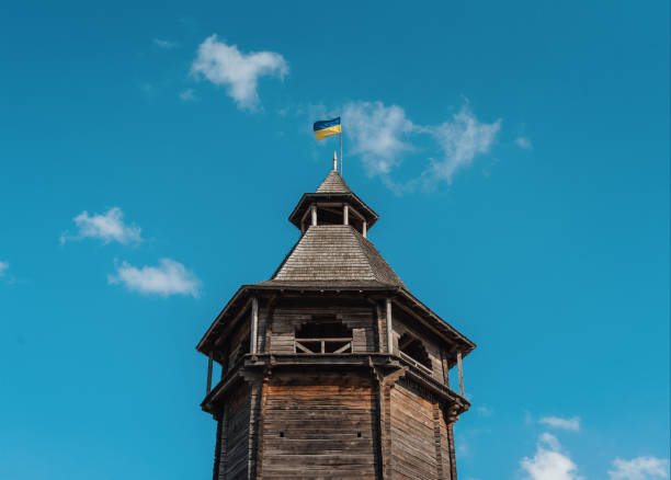 Wooden tower of Baturyn Fortress Citadel with Ukrainian flag flying above it. Old wooden tower against clear teal-blue sky with few small clouds in the background. Baturyn, Ukraine - October 14 2020. baturyn stock pictures, royalty-free photos & images