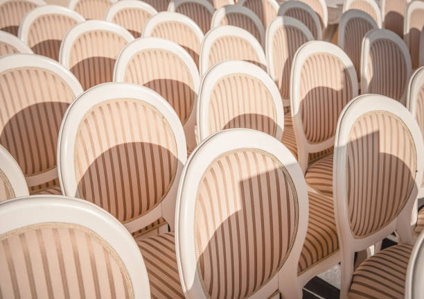 Row of empty chairs in a modern conference room with natural light filtering through blue vertical blinds. Minimalist interior design for business or education.