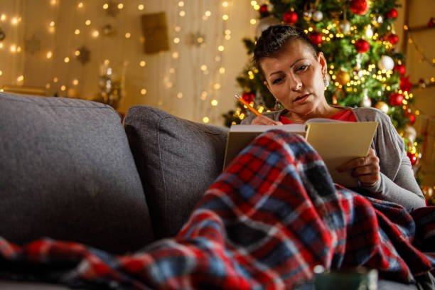 istock Woman journaling on a couch with blanket and Christmas tree decoration 2192120715