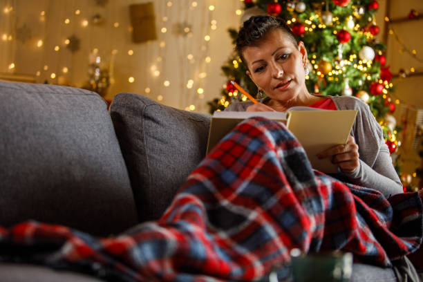 istock Woman Relaxing on Sofa Writing in Notebook During Holiday Season 2192120730